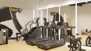 Une salle de sport équipée de tapis de course, de vélos elliptiques et d’un mur recouvert de miroirs.