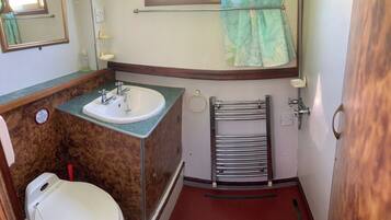 A compact bathroom with a sink, toilet, and towel rack.