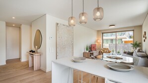 Una cocina moderna con encimera blanca, lámparas colgantes y un amplio ventanal con vistas al exterior.