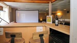 Cocina compacta con encimera de madera, dos taburetes de bar, un refrigerador y una botella de vino.