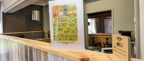 A reception desk with a poster of Newfield Apartment, a wooden counter, and a Wi-Fi sign.