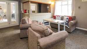 Una sala de estar con dos sofás, una mesa de centro y una pequeña cocina con espejo y encimera.