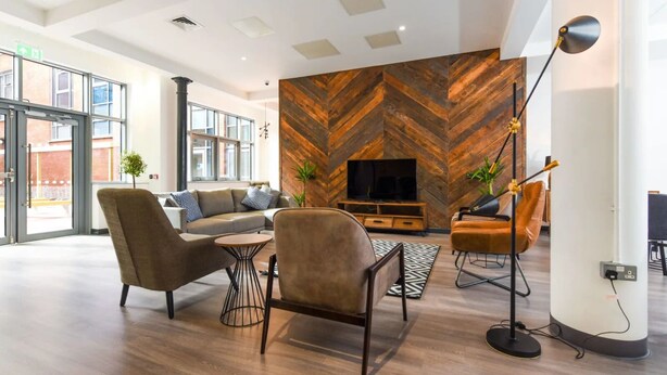 A modern living room with a herringbone-patterned wall, a flat-screen TV, and contemporary furniture. - Student Only Swanston House (Belfast)