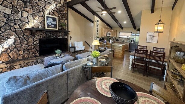A spacious living area with a stone wall, a large sofa, a dining table with chairs, and a kitchen in the background. - Newly Renovated 5 bedroom Condo in Ruidoso (Ruidoso)