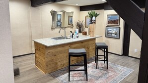 A kitchen with a wooden island, two barstools, a sink, and a mirror. - Newly Renovated 5 bedroom Condo in Ruidoso (Ruidoso)