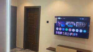 Een moderne woonkamer met een flatscreen televisie aan de muur, een marmeren vloer en een minimalistische salontafel.