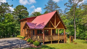 A wooden cabin with a red roof, a porch, and a deck, surrounded by trees. - Stunning  chalet close to Murphy. Hot Tub, Fire Pit, Dog Friendly, Ample Parking (Murphy)