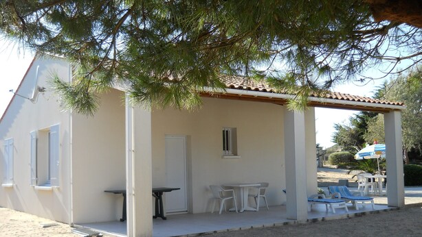 Zona d'estar a l'aire lliure coberta, amb taula i cadires, una porta i una finestra.