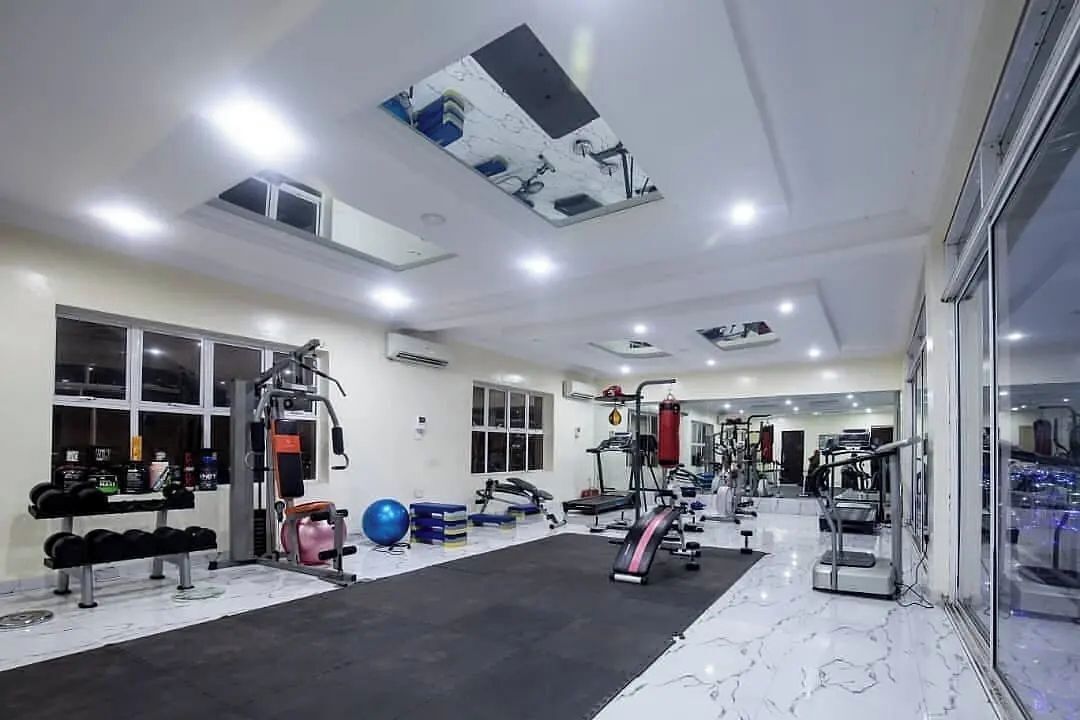 Une salle de sport équipée de divers appareils d’exercice, dotée d’un espace avec des tapis noirs et d’une fenêtre donnant sur la ville.