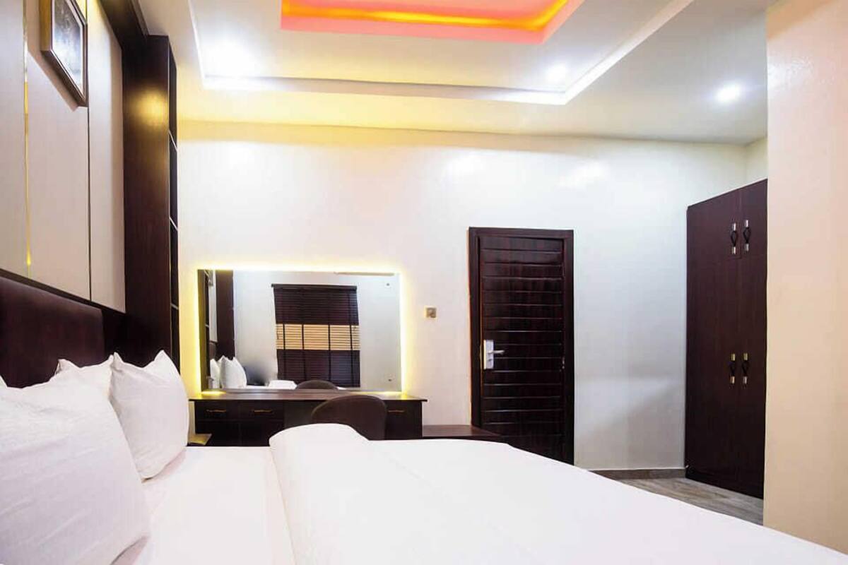 A hotel room with a large bed, a desk with a mirror, and two wardrobes.