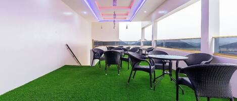 A room with artificial green turf, wicker furniture, and a view through large windows.