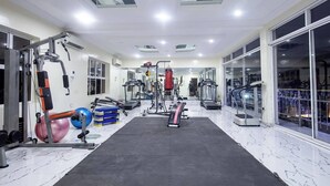 Un gimnasio con diferentes máquinas de ejercicio, un espejo grande y un ventanal.