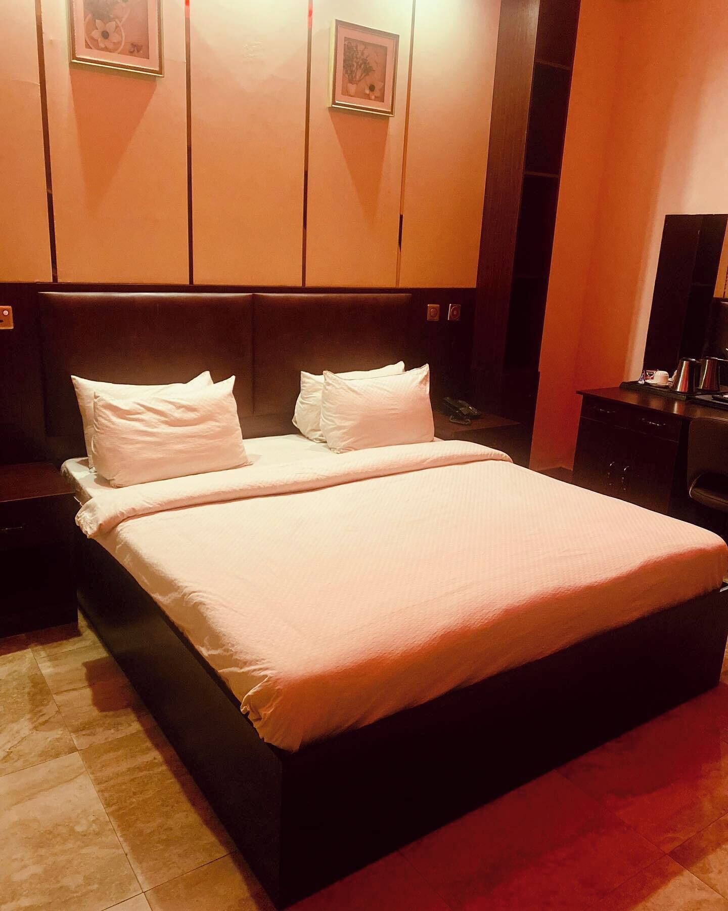 Una cama doble con cabecera, dos mesitas de noche y una mesilla auxiliar.