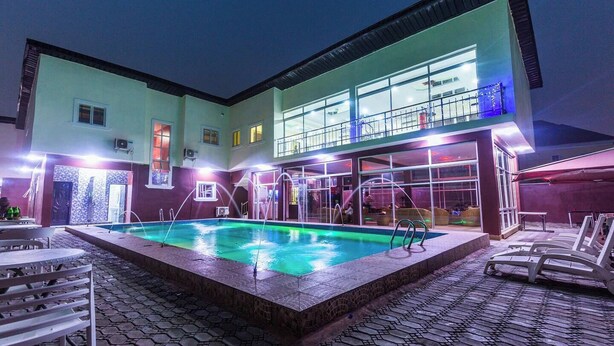 Una piscina interior con suelo de baldosas, rodeada de sillones de descanso y una zona de estar cubierta.