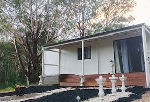 Simple, functional design with a covered porch and lush garden surroundings.