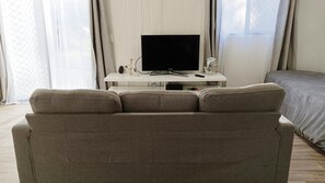 Relax in a serene space with a large flat-screen TV, comfortable sofa, and a cozy bed.