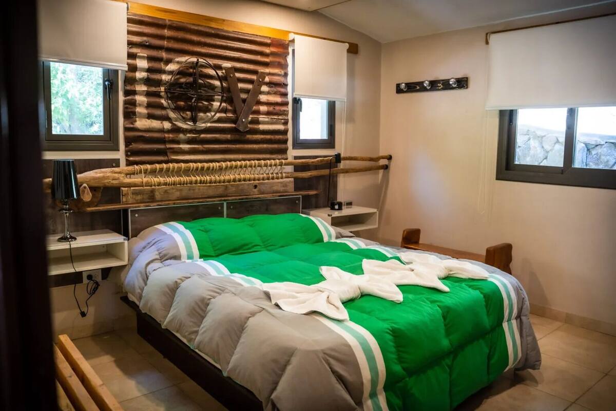 A room with a bed, a wooden headboard, a wall-mounted fan, and a window.