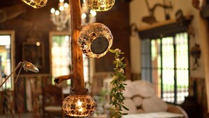 Ein gemütliches Interieur mit hängenden, kugelförmigen Lampen, einem Holzbalken und einer Pflanze.