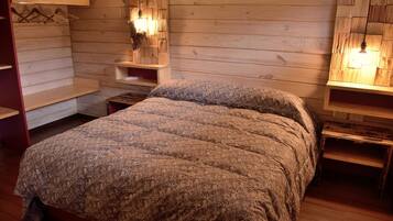 A wooden cabin-style bedroom with a bed, wooden shelves, and wall-mounted lights.