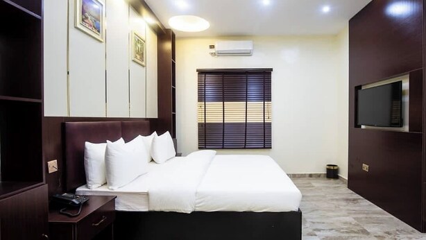Habitación de hotel con cama, mesita de noche, televisor y una obra de arte en la pared.