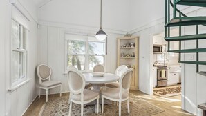 Un coin repas comprenant une table ronde, quatre chaises et un luminaire suspendu.