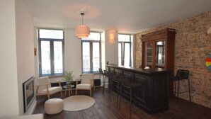 Une cuisine moderne avec un coin bar, un plancher en bois et de grandes fenêtres équipées de stores.