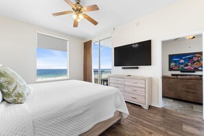 A bedroom with a bed, a ceiling fan, a TV, and a painting. - Spanish Key 306 (Pensacola)