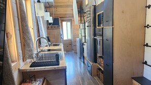 Une cuisine de taille réduite, dotée de meubles de rangement en bois, d’un four encastré et d’un évier.
