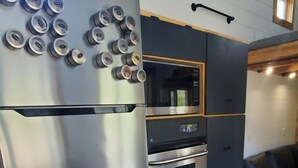 Une cuisine compacte équipée d’un réfrigérateur en acier inoxydable, d’un four encastré et d’un four à micro-ondes.