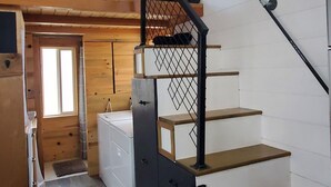 Un escalier avec des marches en bois et une rampe en métal noir, menant à un étage supérieur.