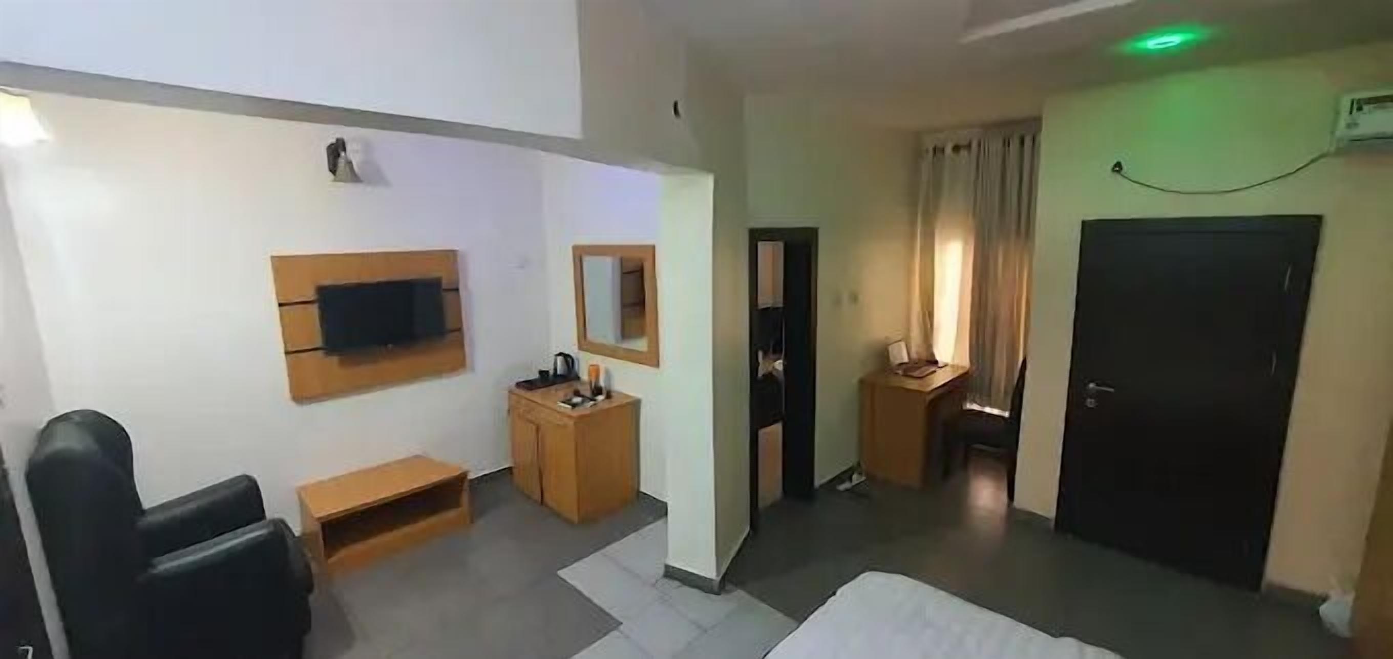 Een hotelkamer met een bed, een bureau, een stoel, een televisie, een spiegel en een kledingkast.