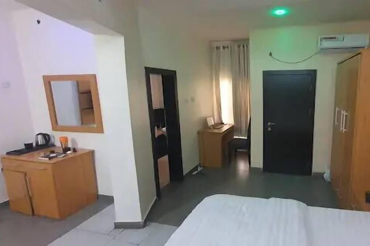 Une chambre d’hôtel avec un lit, un bureau, une chaise, une armoire et une porte de salle de bain.