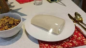 A table with a white plate holding a rectangular food item, a bowl with a mixed dish, and a decorative basket.