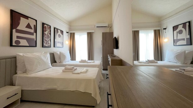 Una habitación de hotel con dos camas, un escritorio de madera, un televisor y obras de arte en las paredes.