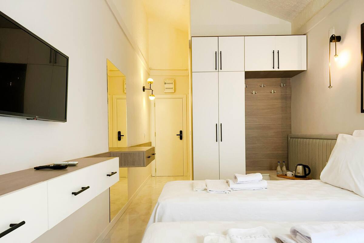A hotel room with a bed, a TV, a wardrobe, and a bathroom.