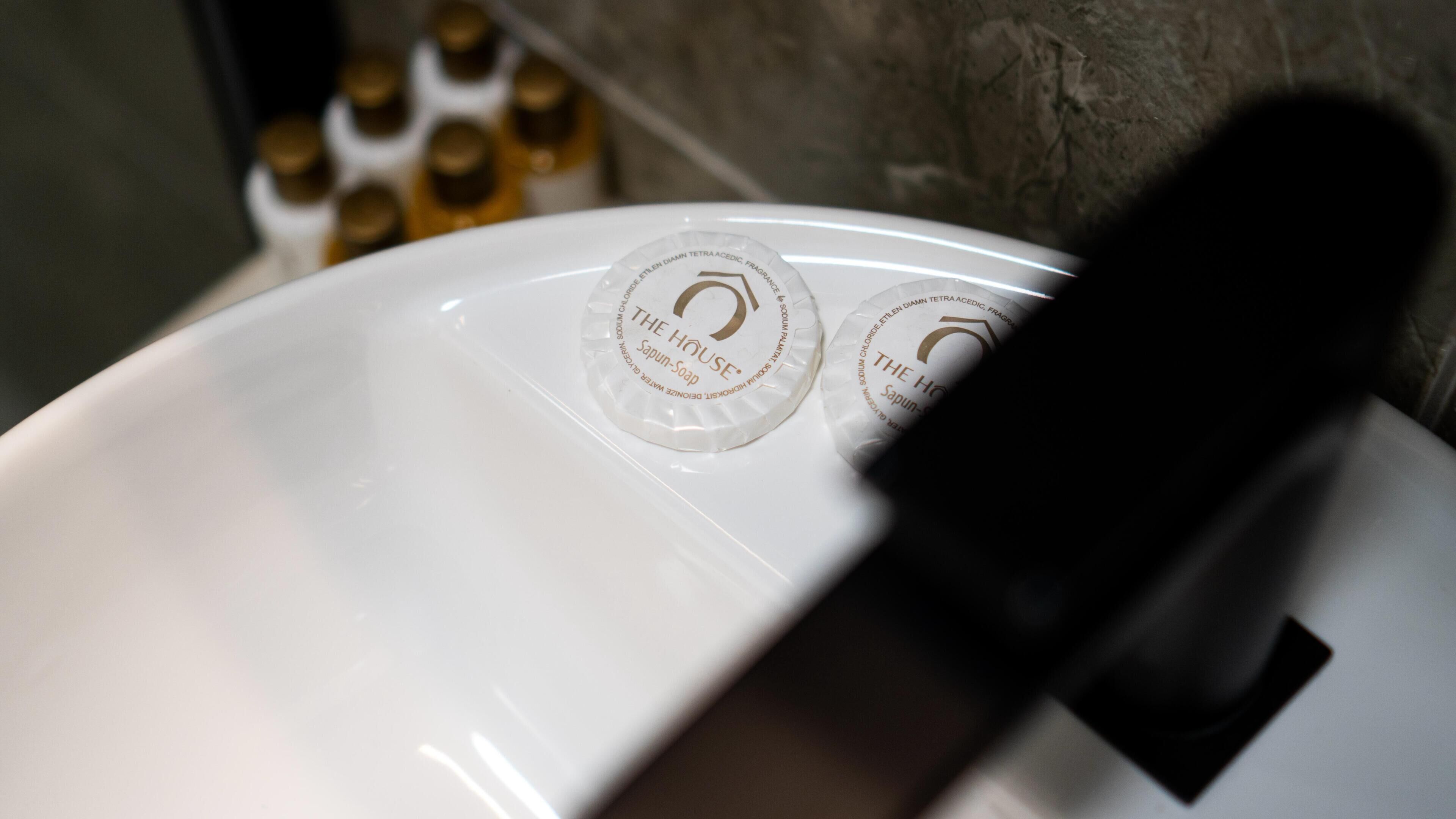 A white sink with two soap dispensers labeled "The House Soap".