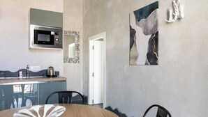 A modern kitchen with a microwave, a sink, and a coffee maker. There is a dining table with chairs and a decorative glass piece on it.