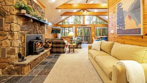 A cozy cabin interior with a stone fireplace, wooden beams, a couch, and a poster on the wall. - The Robin's Nest, a cozy 3-bedroom cabin in Lake Harmony with Firepit, AC, WiFi (Lake Harmony)