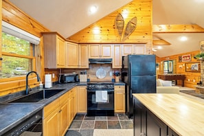 Kitchen with central island, black stove, refrigerator, and sink, perfect for meal preparation and dining.