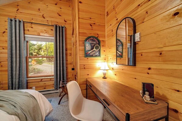 Relax in a serene space with a comfortable bed, a stylish chair, and a desk for work or relaxation.