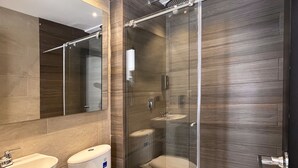 Ein modernes Badezimmer mit einer Duschkabine aus Glas, einer weißen Toilette und einem Waschbecken.