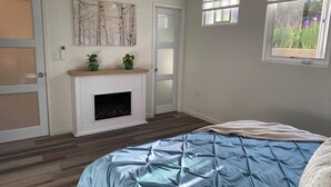 Ein Schlafzimmer mit Bett, Kamin, Fenster und Tür.