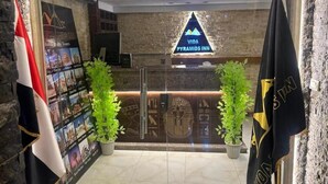 The entrance to VIDA Pyramids Inn with a reception desk, Egyptian-themed decor, and flags. - Vida Pyramids Inn (Giza)