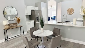 A modern kitchen with white cabinets, a built-in refrigerator, and a round dining table with four chairs. - Luxury Florida Villa with Private Pool - Free Heating (Kissimmee)