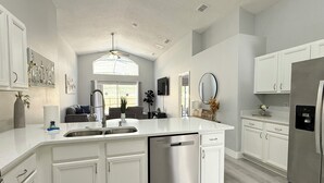 A modern kitchen with white cabinetry, a stainless steel dishwasher, and a built-in refrigerator. - Luxury Florida Villa with Private Pool - Free Heating (Kissimmee)