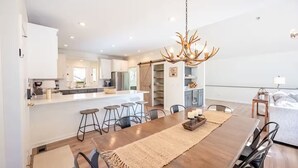 A modern kitchen with a central island, bar stools, and a chandelier.