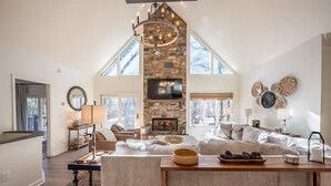 A spacious living area with a stone fireplace, a large window, and a cozy seating arrangement.