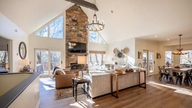 A spacious living area with a stone fireplace, a large TV, and a dining area with a long table.