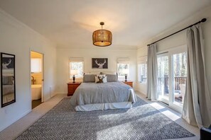 Een slaapkamer met een groot bed, een kroonluchter, een raam met gordijnen en uitzicht op de omgeving.