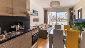 A modern kitchen with a built-in oven and a dining area with a table and chairs. - Appart climatisé, 400m des Plages + accès Piscine (Biarritz)